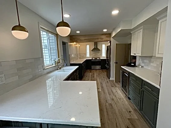 Long galley kitchen design in Willow Grove, PA with two-tone green and white cabinetry, pendant lighting, stainless steel appliances, and exposed beam