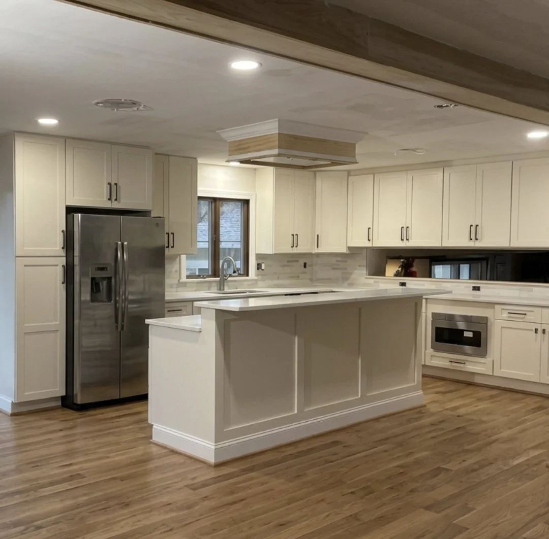 JWD Contractors kitchen remodel in Perkasie, PA with off white cabinetry, a large island, stainless steel appliances, and wood flooring.