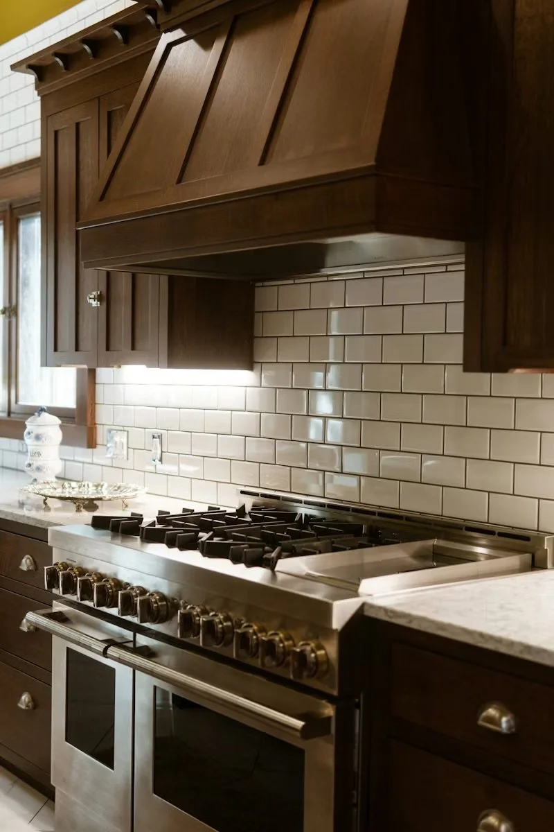 Kitchen with dark wood cabinets, white subway tile backsplash, and stainless steel gas stove with oven.