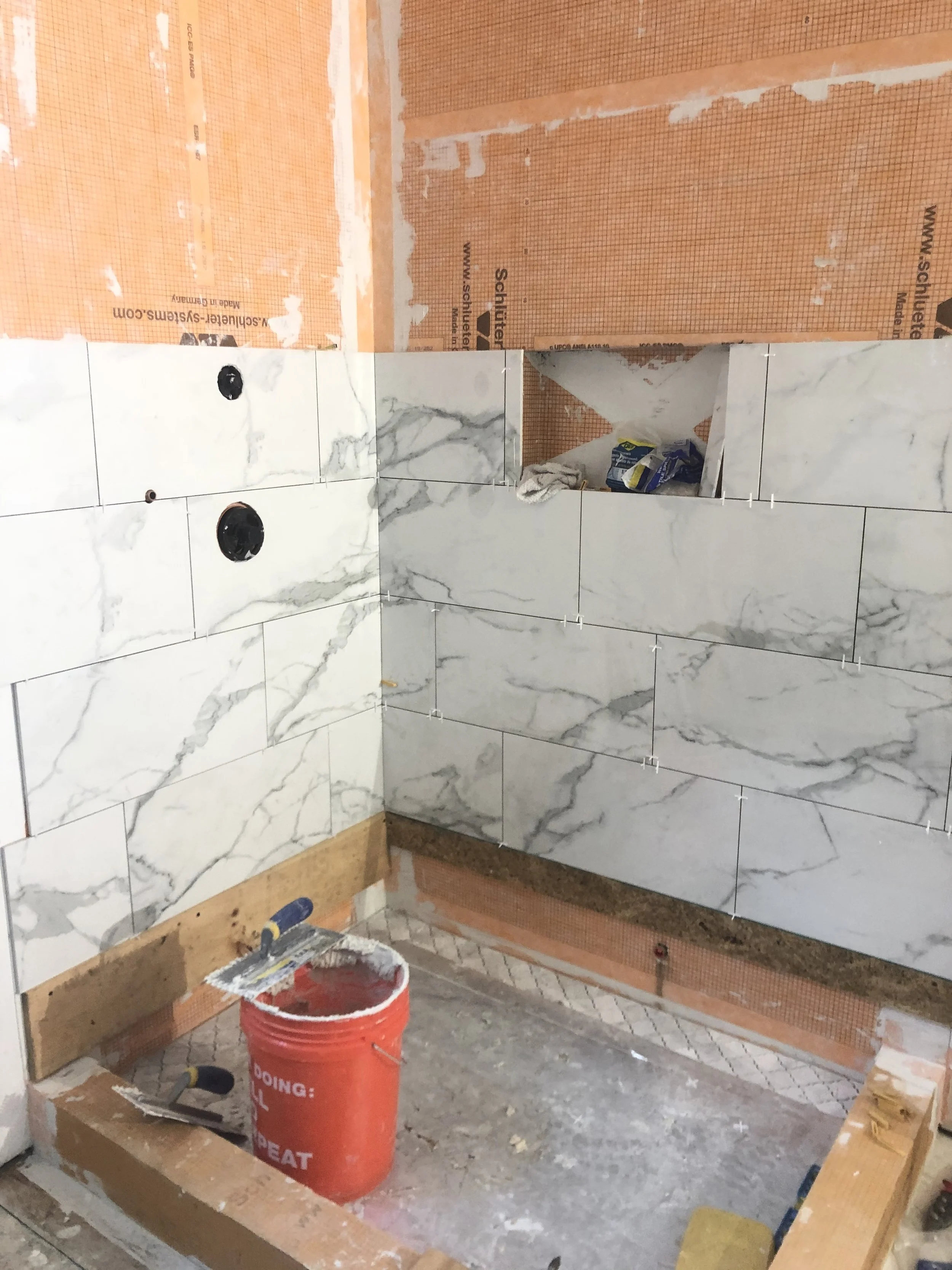 Marble-look shower wall tile and mosaic shower floor being installed during a Upper Moreland Township, PA bathroom remodel.