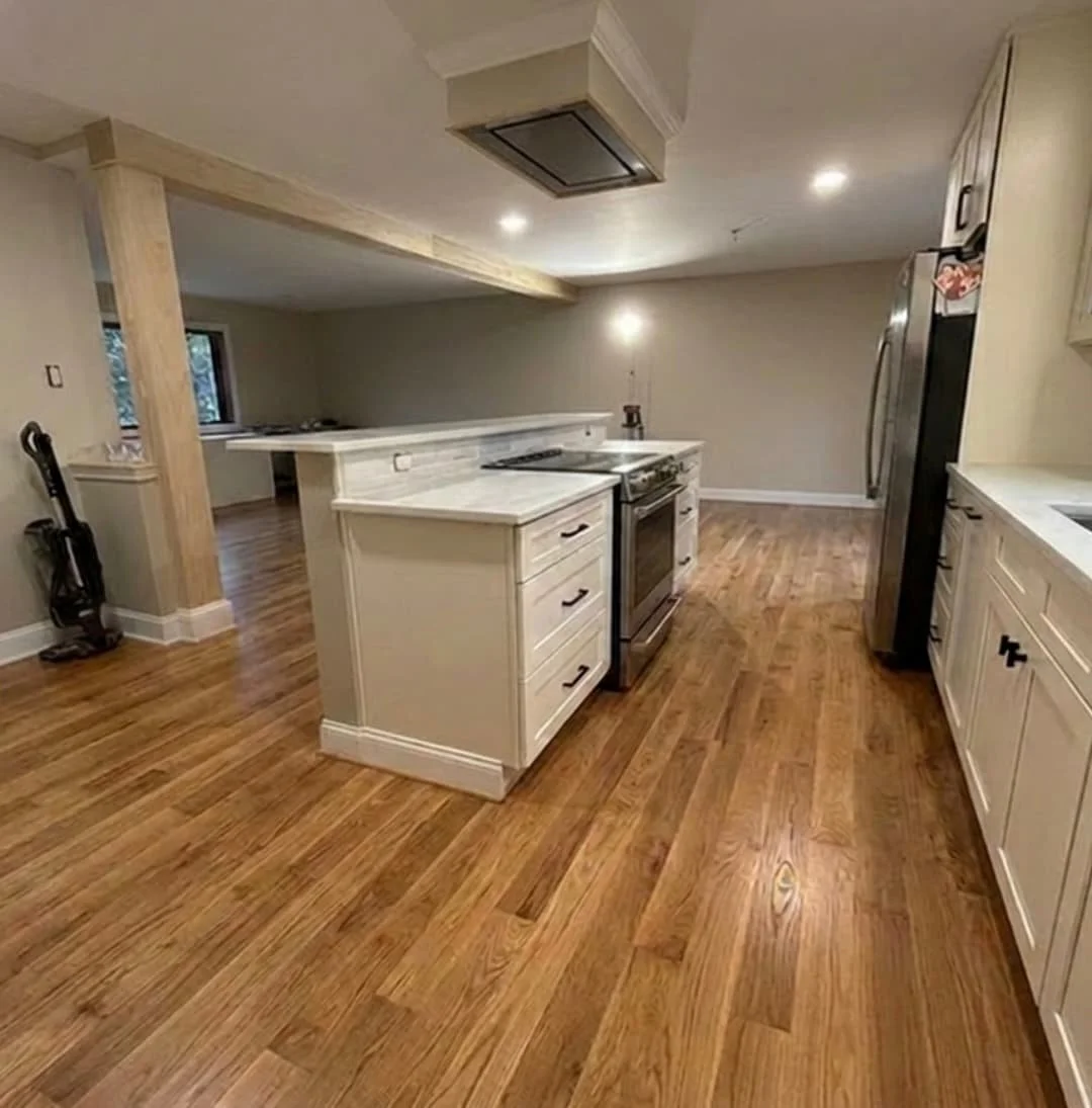 Large custom kitchen island with built-in cooktop, shaker cabinetry, quartz countertops, and exposed ceiling beam in a Perkasie kitchen remodel.