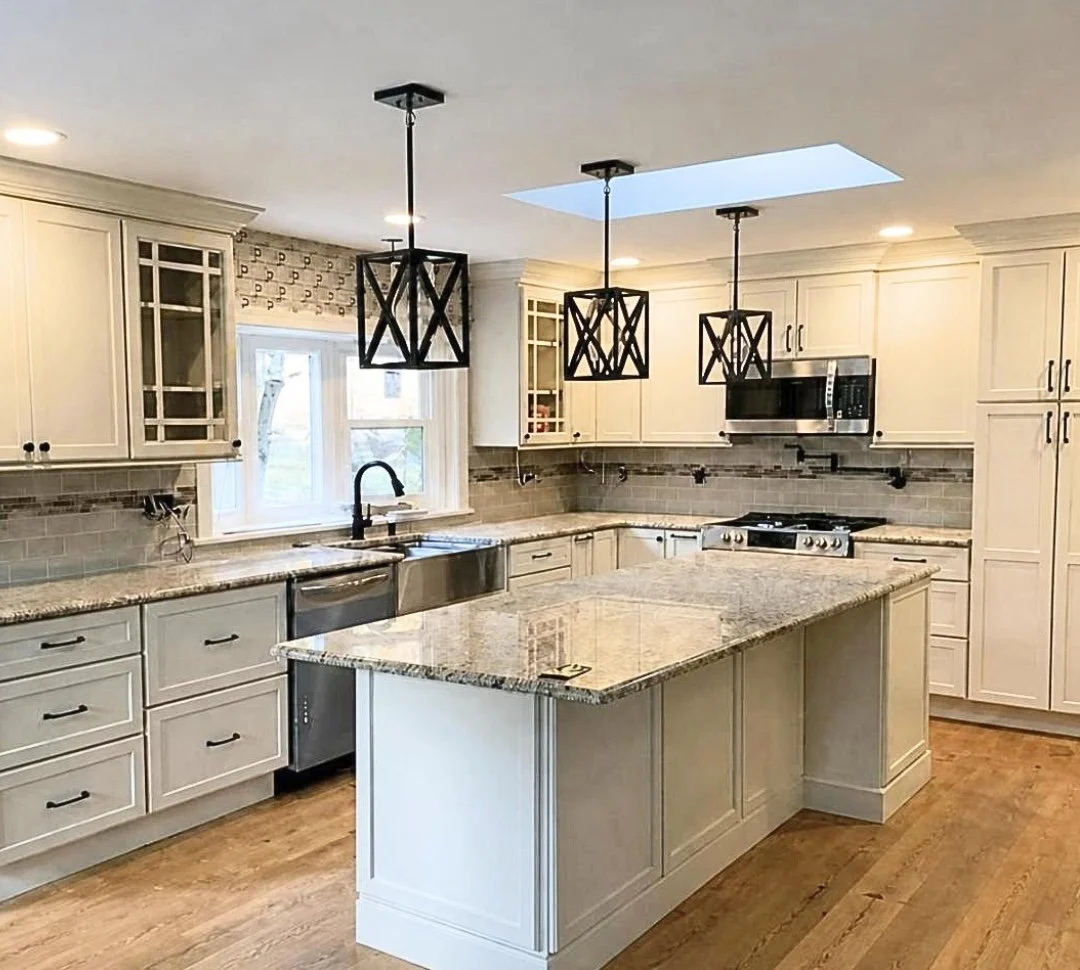White shaker kitchen island with granite countertops, lantern pendant lightings, and skylight above