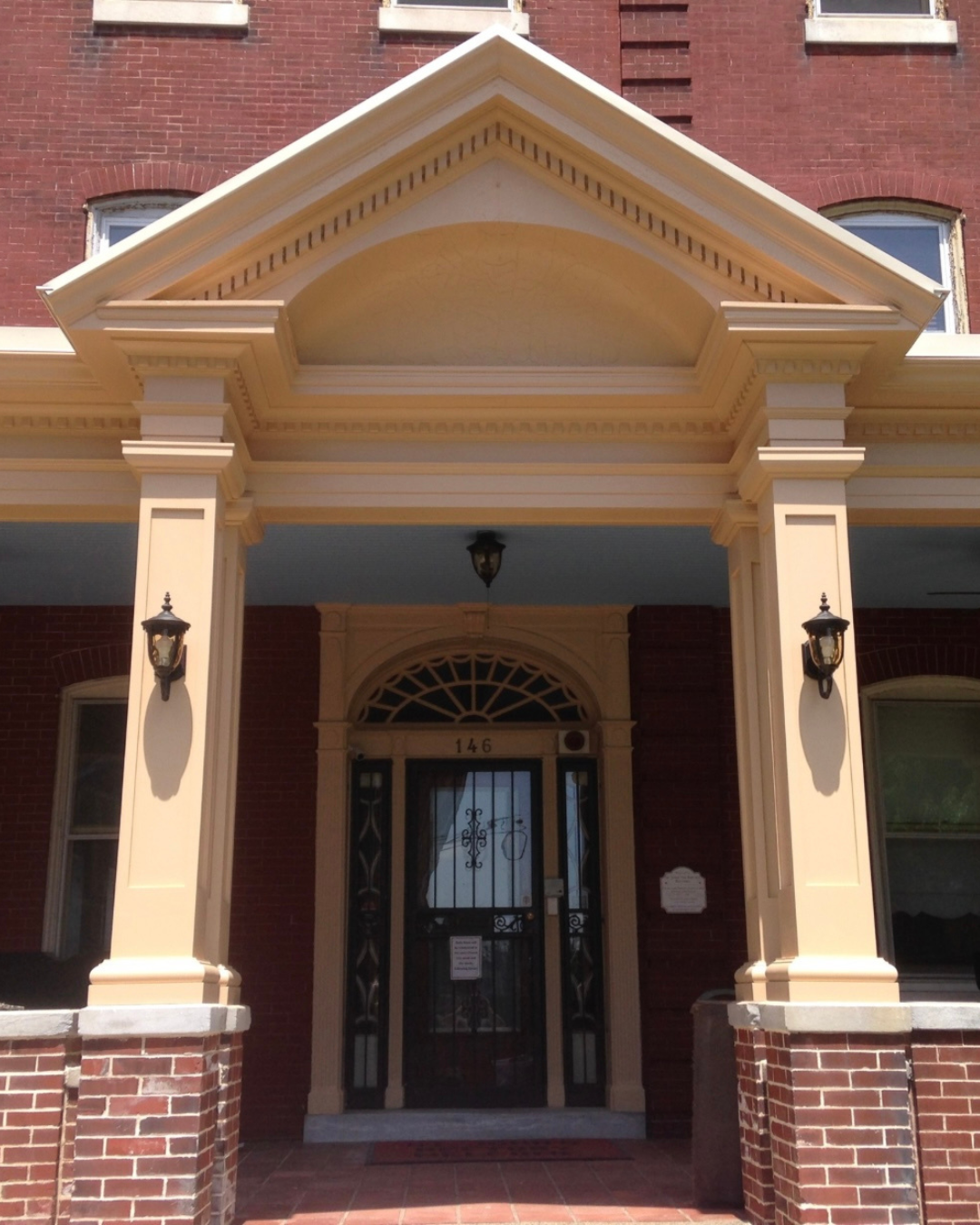 Restored portico entrance on a historic Philadelphia building featuring dentil molding, pediment detail, and brick pier columns