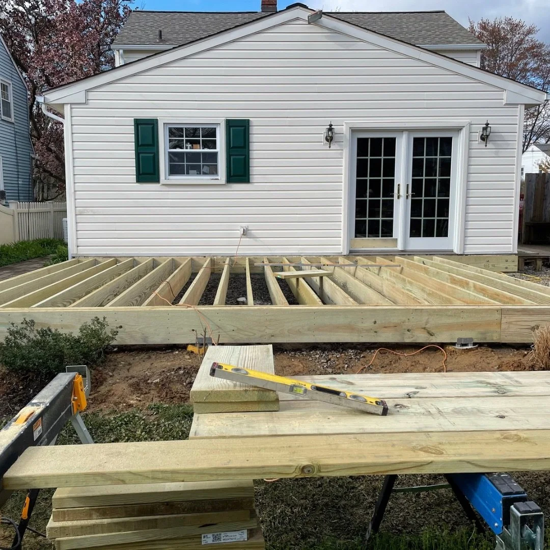 New deck framing under construction in Warrington, PA with pressure-treated joists on. Deck footing blocks