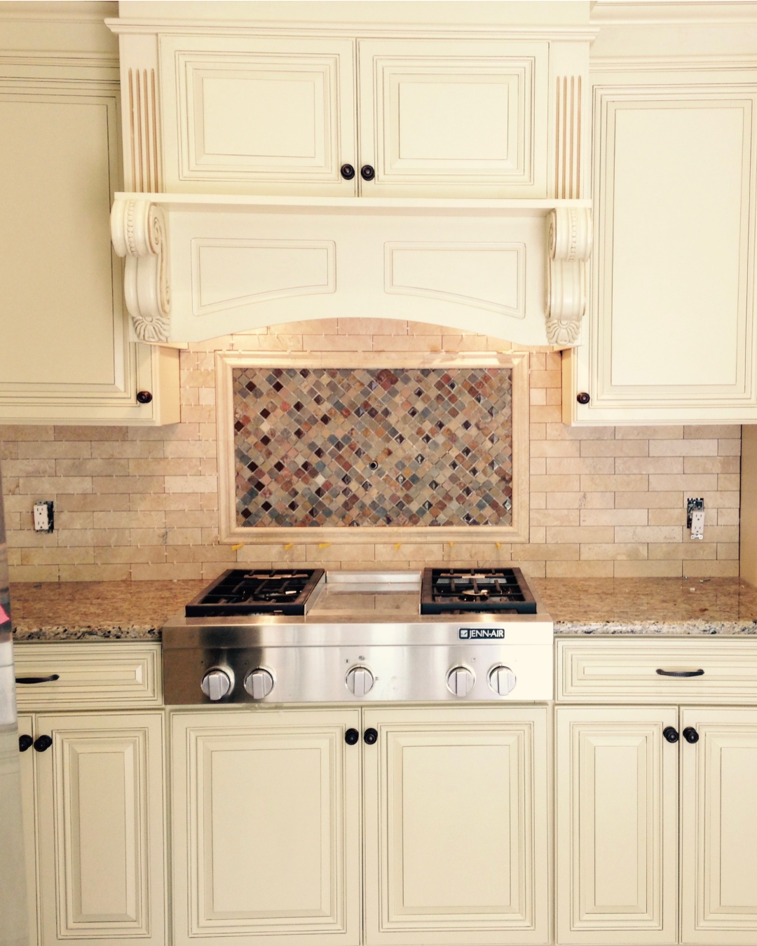 Creamed glazed kitchen remodel in Willow Grove, PA by JWD Contractors featuring granite countertops, travertine tile backsplash with mosaic accent, and stainless steel cooktop