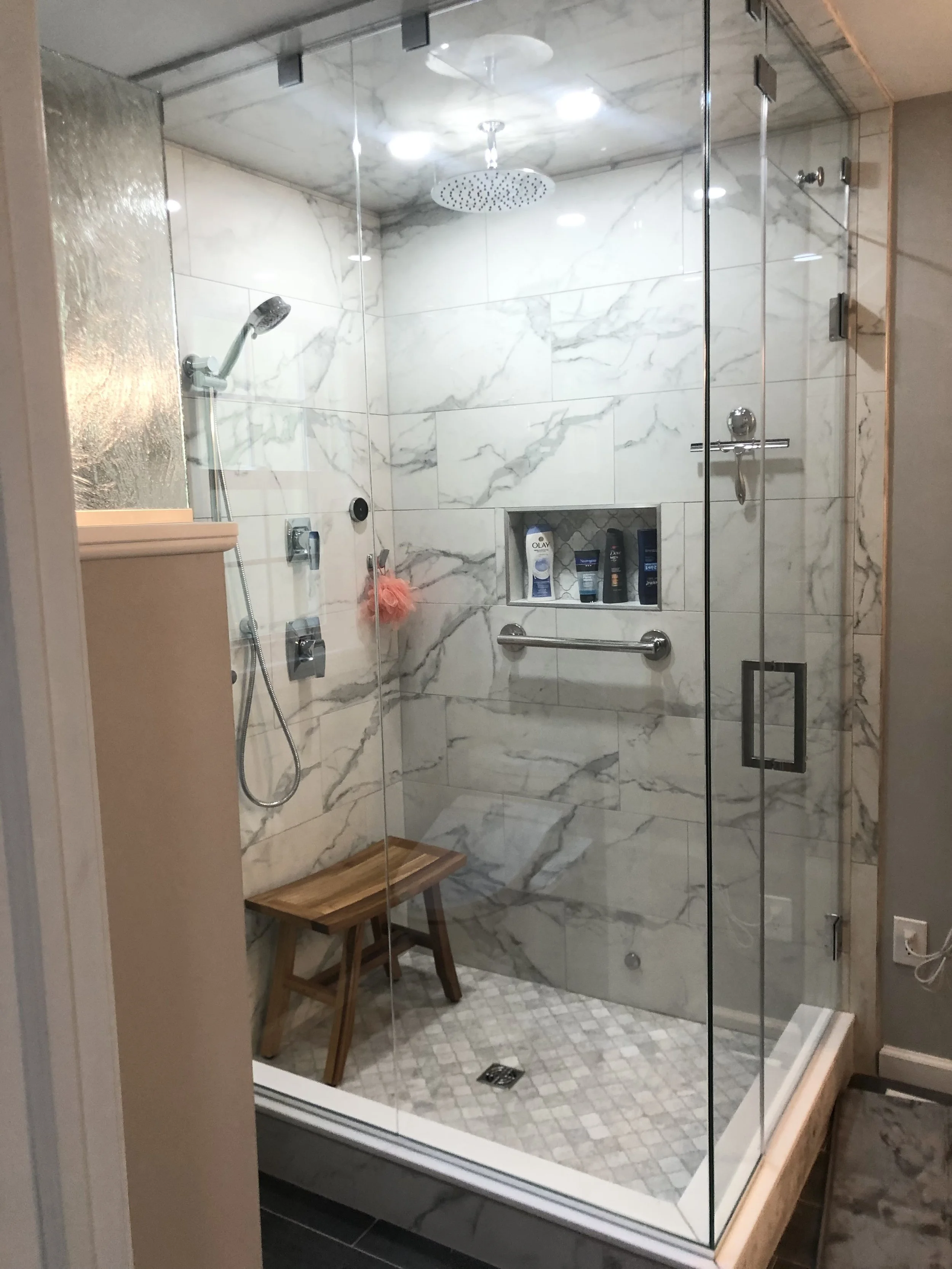 Finished walk-in shower in an Upper Moreland Township, PA bathroom remodel with marble-look tile, glass enclosure, niche, and grab bar.