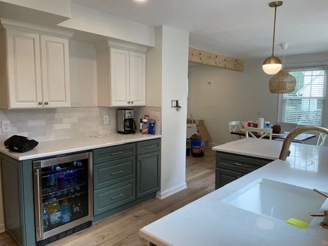 Custom beverage station with two-toned deep green and white cabinetry, quartz countertops, subway tile backsplash, and a built-in wine refrigerator in a Willow Grove, PA kitchen remodel.