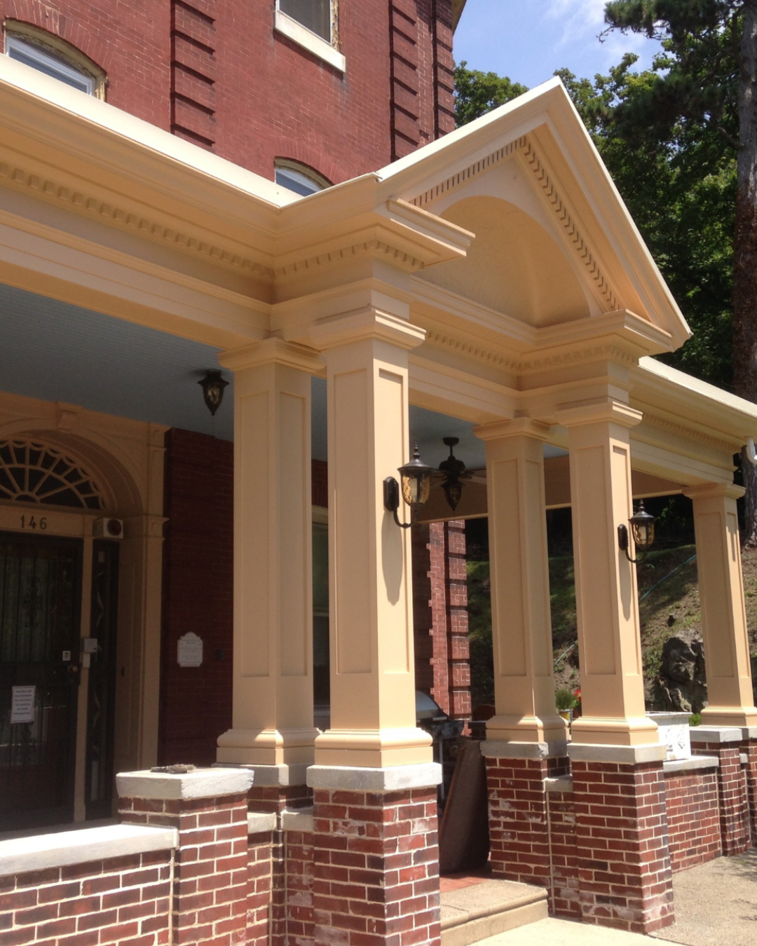 Angled view of restored porch columns and pediment on a historic Philadelphia brick building