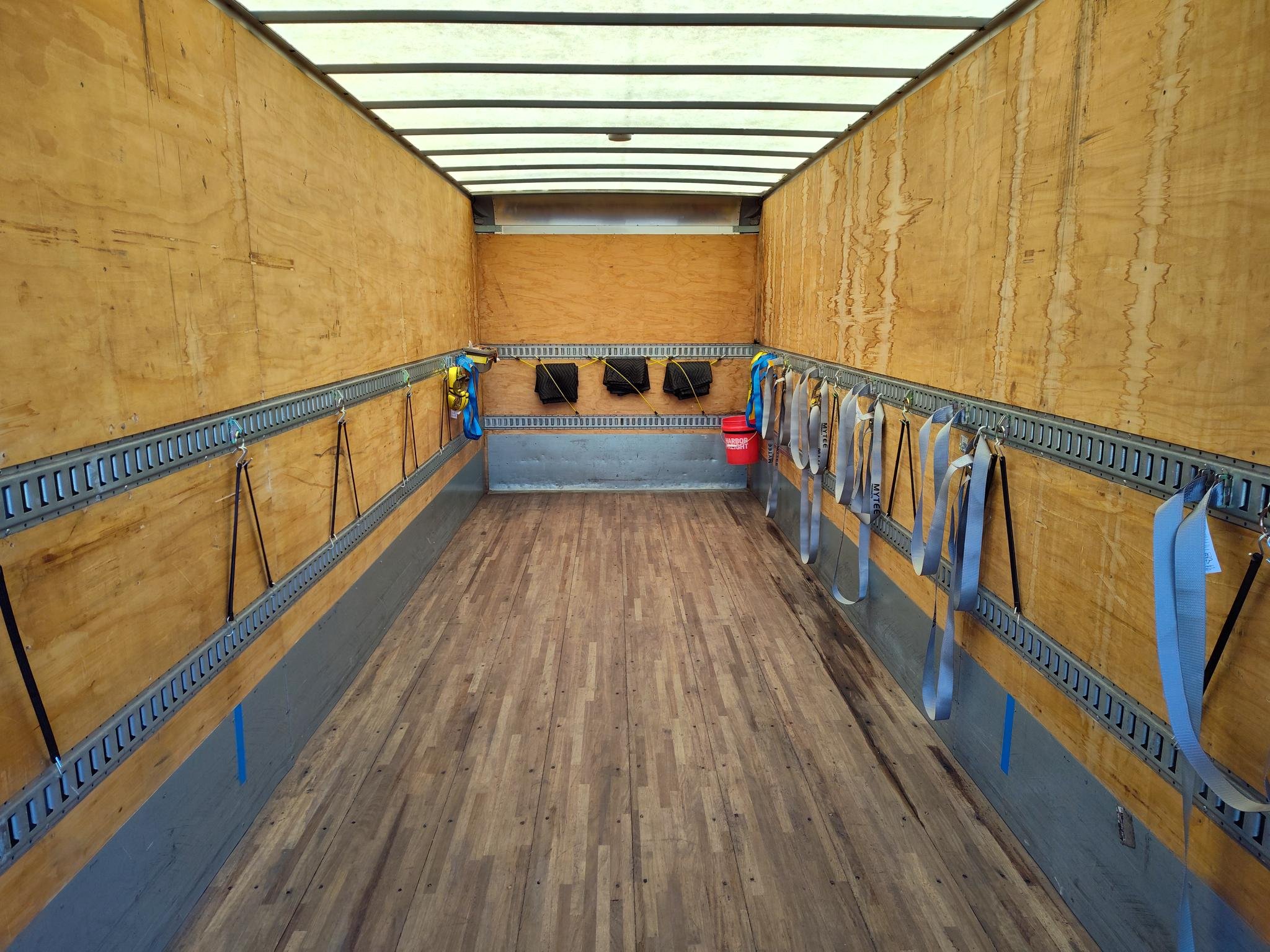 Empty enclosed HINO 268 truck bed with wooden walls, and floor.
