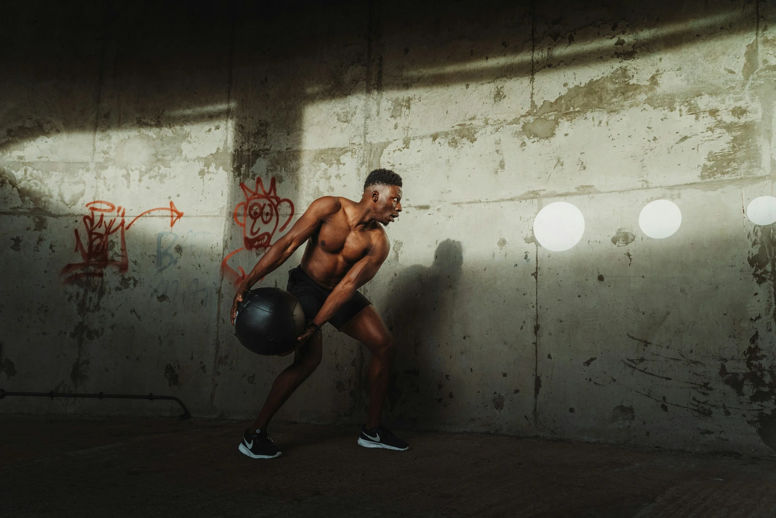 Man performing a rotational med ball toss against a concrete wall
