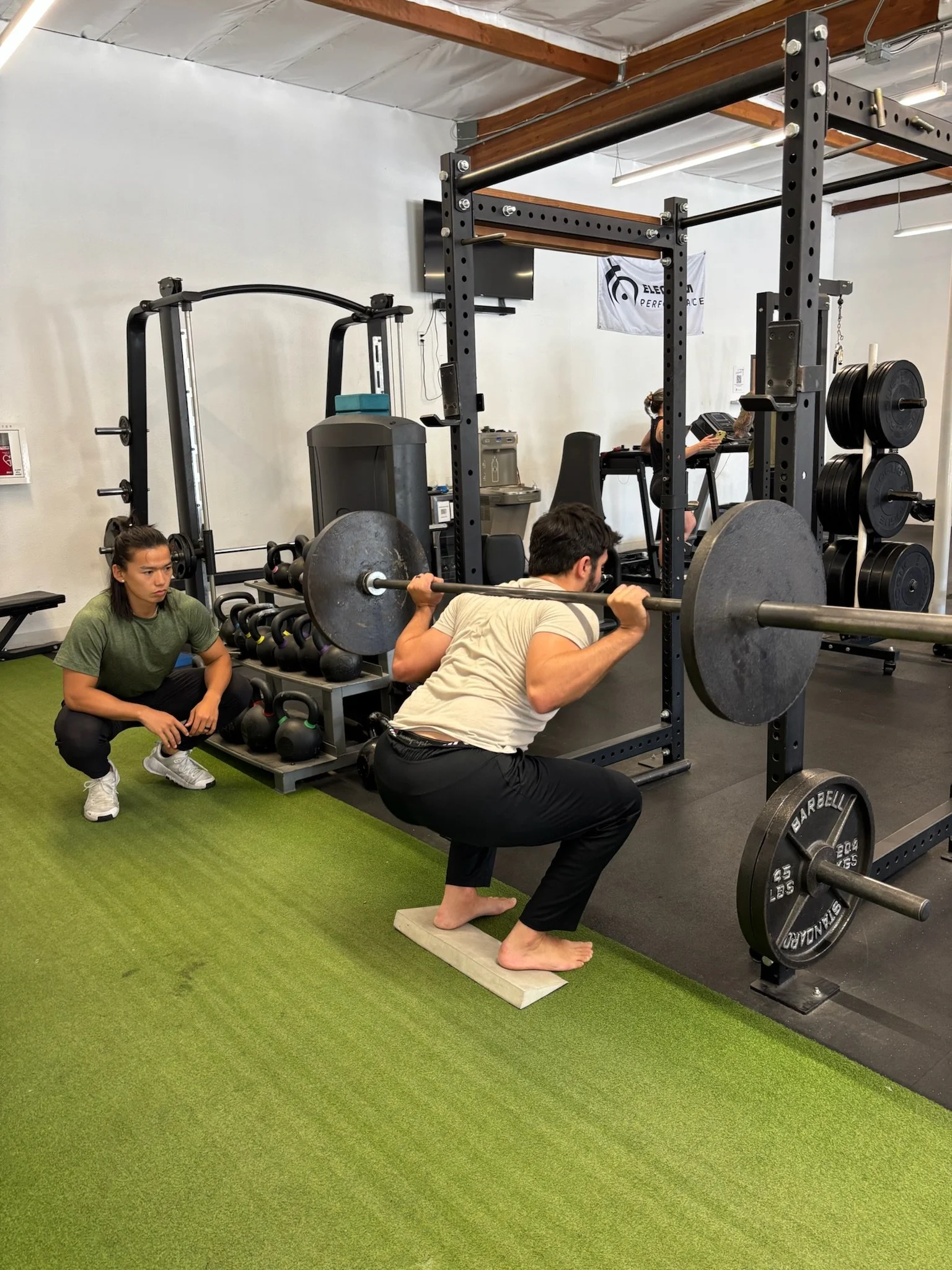 Hector Wang supervising a squat with a patient during a physical therapy session.