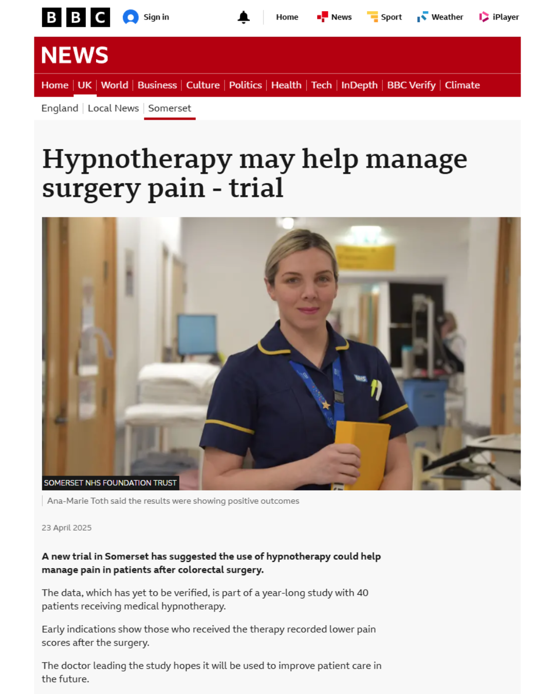 A news website article with the headline "Hypnotherapy may help manage surgery pain - trial." The image features a woman wearing a navy blue NHS uniform with yellow accents, standing in a hospital corridor holding a yellow tablet or notebook. The background shows hospital equipment and another person working at a desk.