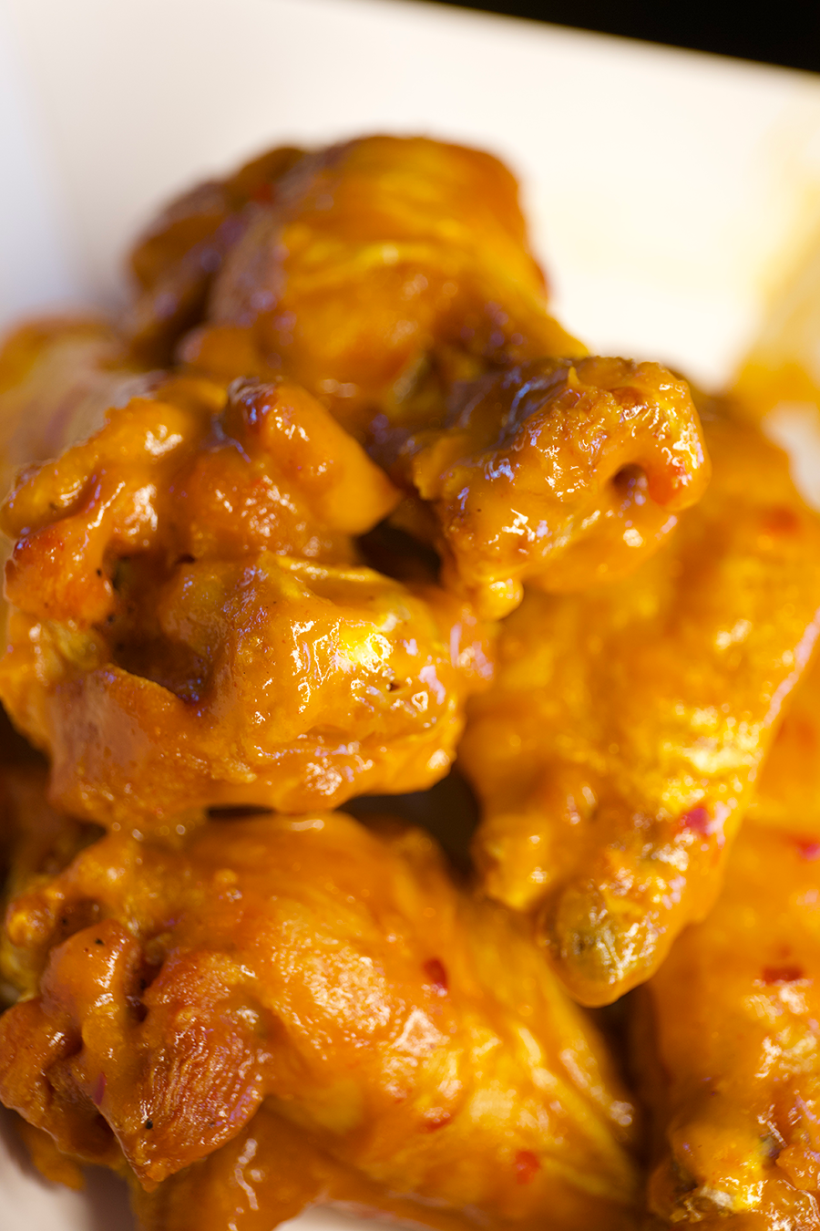 Close-up of glazed chicken wings coated in sauce.