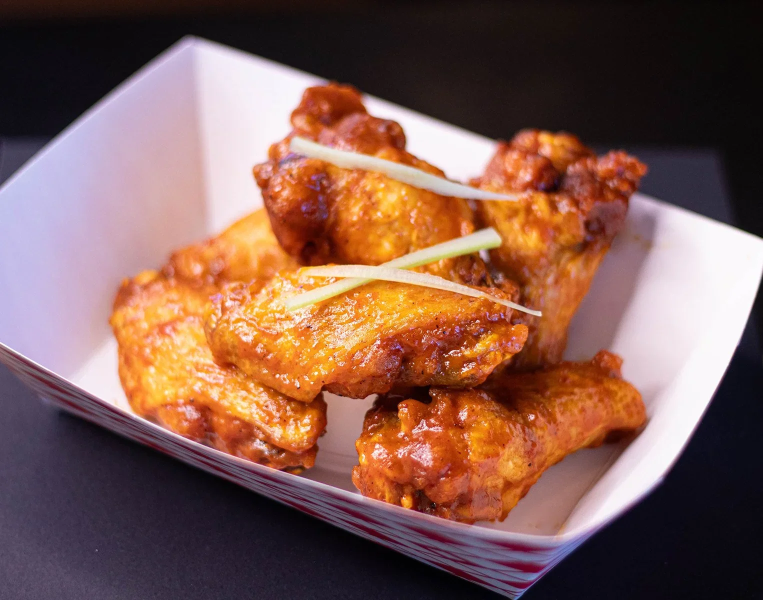 A white tray with three pieces of fried chicken, garnished with thin slices of green onion.