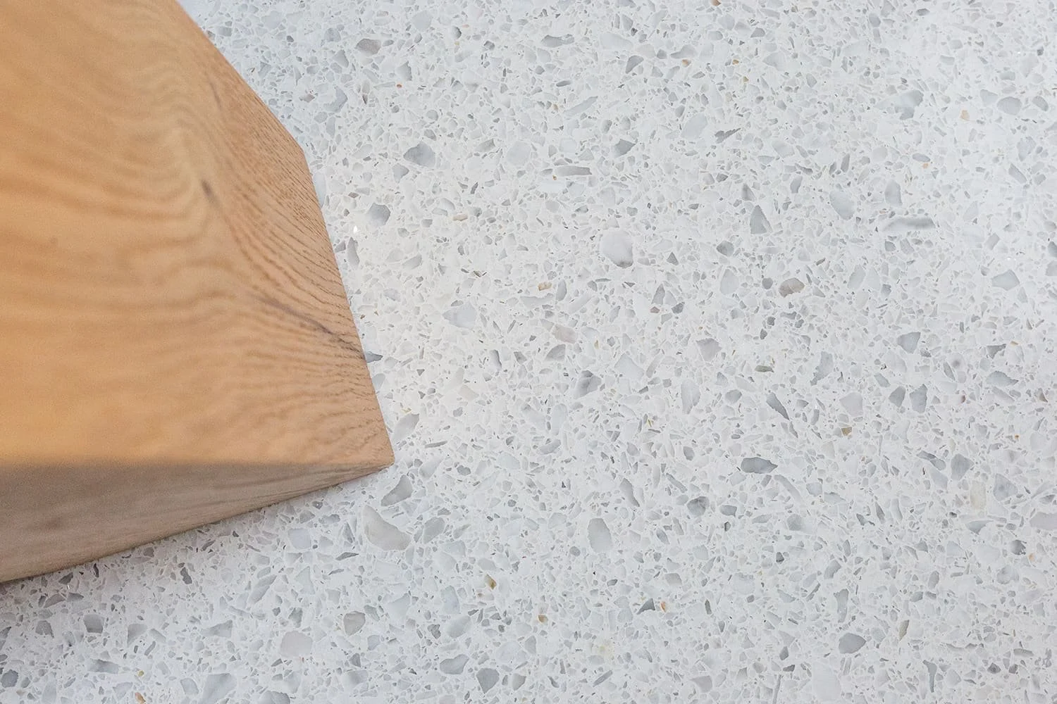Close-up of a wooden block on a white terrazzo surface.