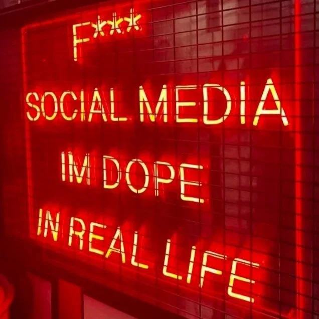 Red neon sign with the words "F*** SOCIAL MEDIA I’M DOPE IN REAL LIFE" in capital letters.