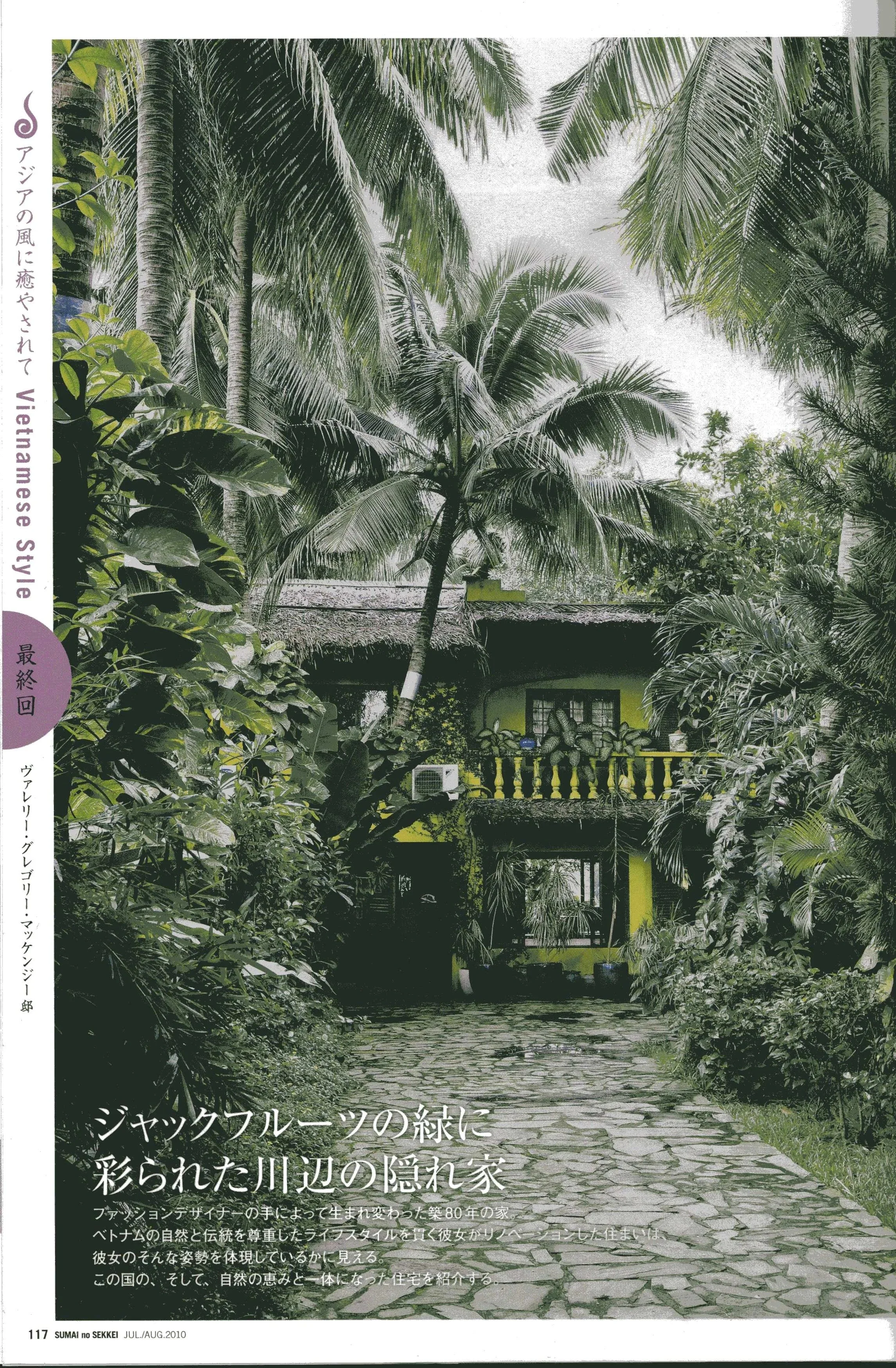 A lush tropical scene showing a cobblestone pathway leading to a bright yellow house surrounded by tall palm trees and dense greenery with Japanese and English text on the left side and bottom of the image.