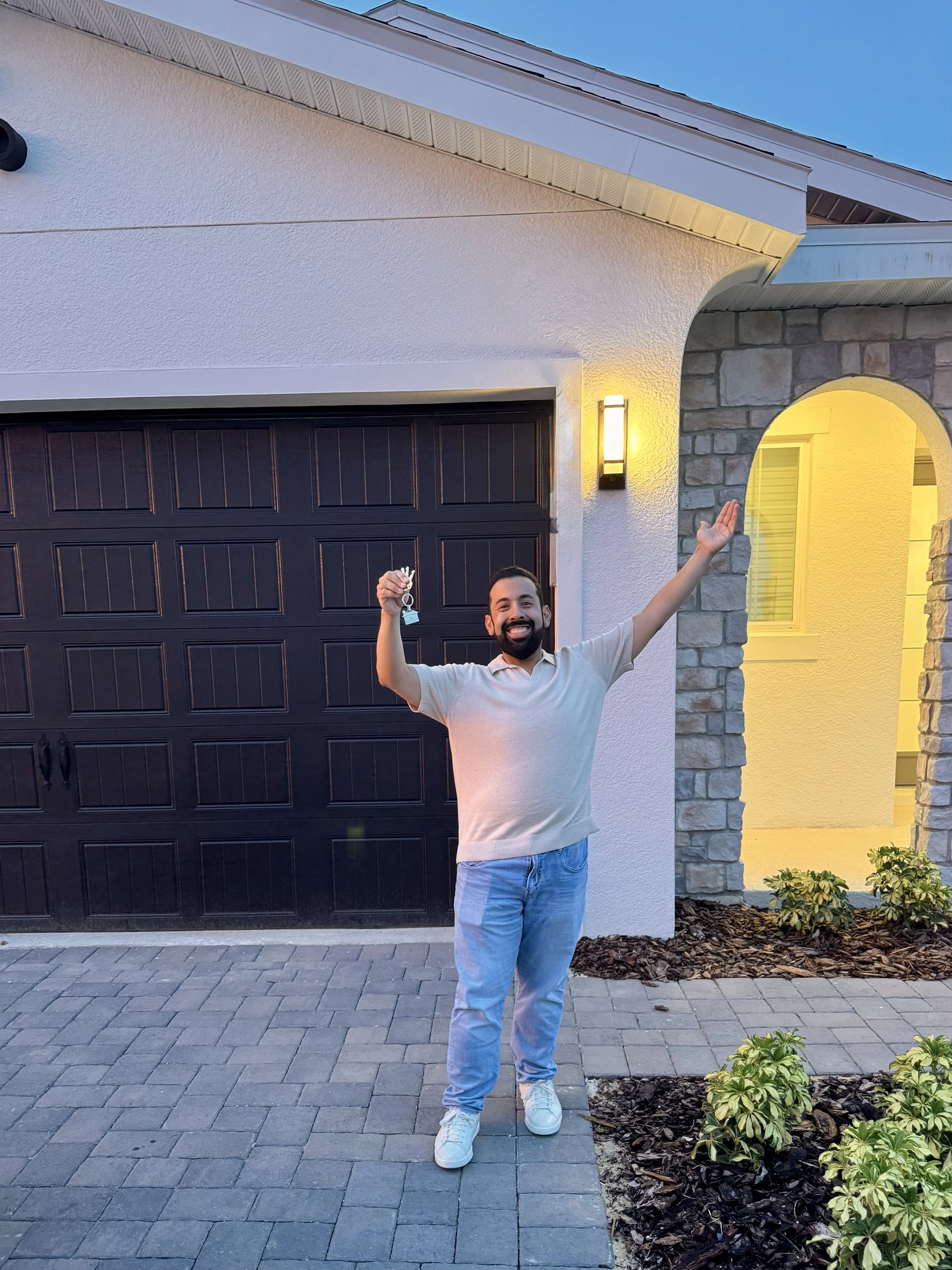 Jose Elias-Torres standing outside his first home in Minneola, Florida on closing day, holding the keys after saving for eight years.