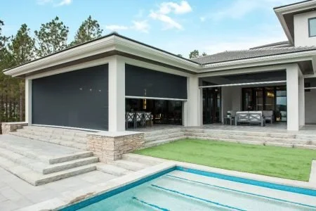 Modern house with large windows, a pool, and outdoor seating area.