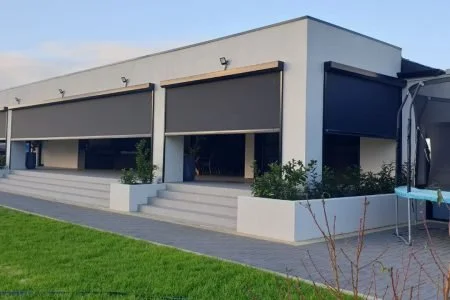 Modern commercial building with large windows, steps leading to entrances, and landscaped surroundings.