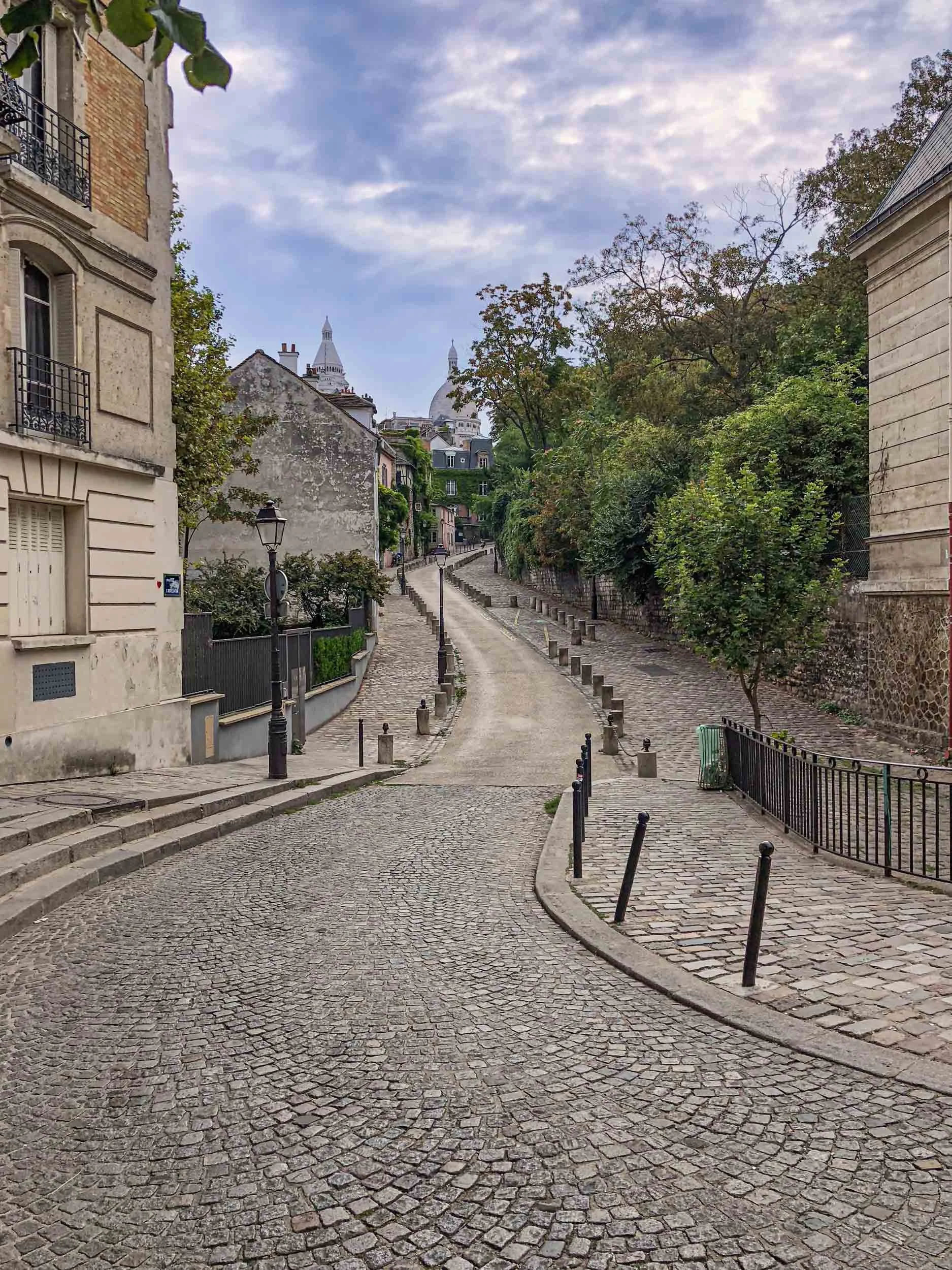 A picturesque street in Montmartre which is in the 18th arrondissement of Paris. Rue de L'abreuvoir leads up through shops, cafes, an outdoor market and ends at the famous church Basilique du Sacré-Cœur.