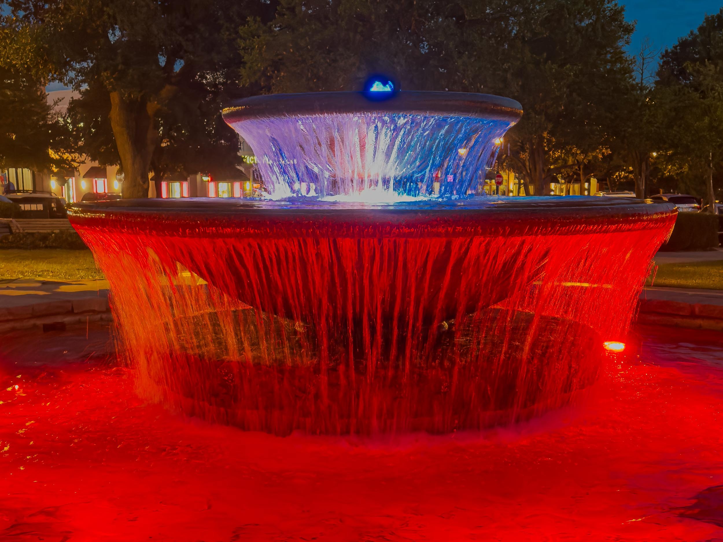 This fountain in Southlake Town Square (Texas) is inspired by traditional Italian piazzas. It is beautifully illuminated at night, casting vibrant, shifting colors across its streams.