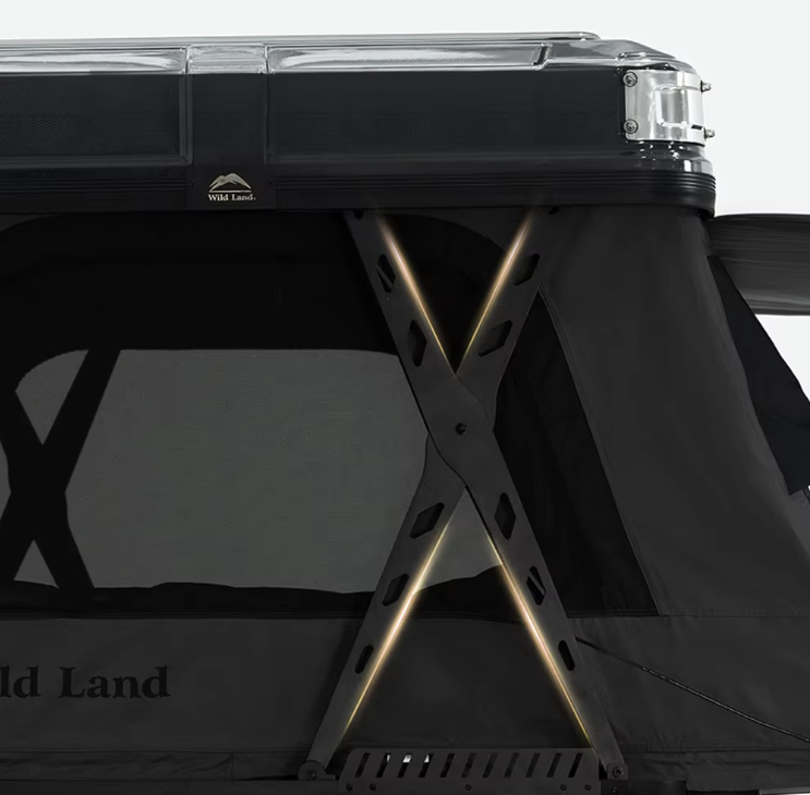 Close-up of a rooftop tent with a black frame and a clear roof, set up on a vehicle, with a gray fabric side wall displaying the brand "Wild Land," supported by crossbars with integrated lighting.