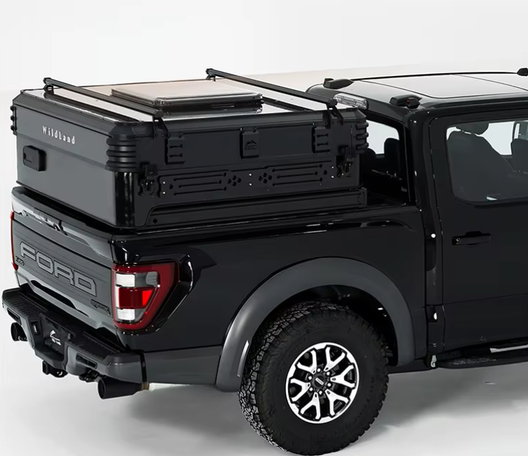 Black Ford pickup truck with a rooftop cargo box and a large storage container in the truck bed.