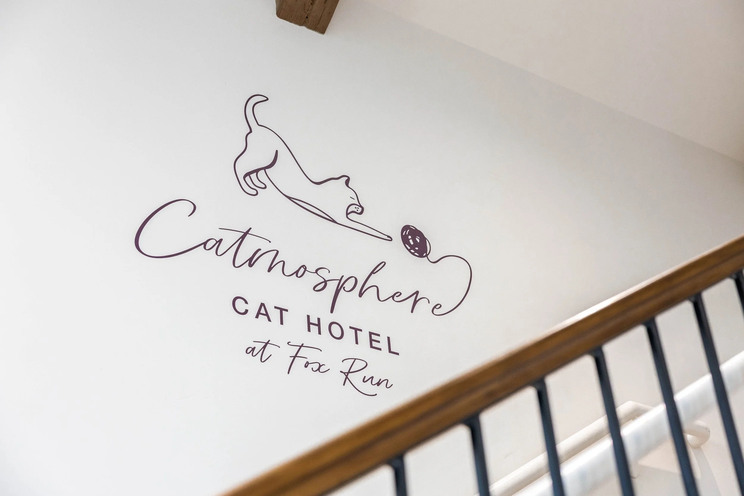 Sign for Catmosphere Cat Hotel at Fox Run with a minimalist outline of a cat and text.