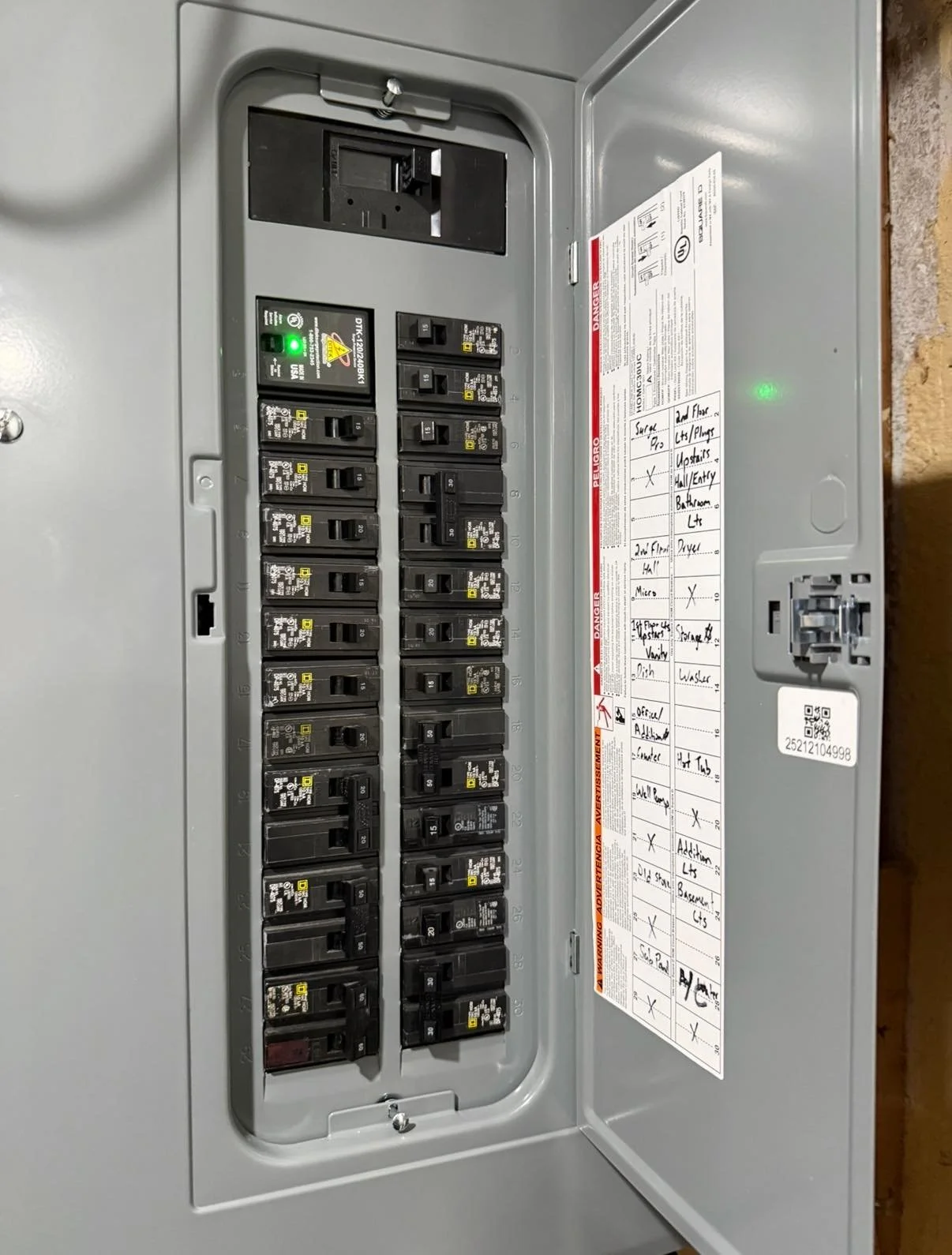 Interior of an electrical breaker box with multiple switches and a handwritten maintenance checklist on the inside of the door, including notes on different circuits.