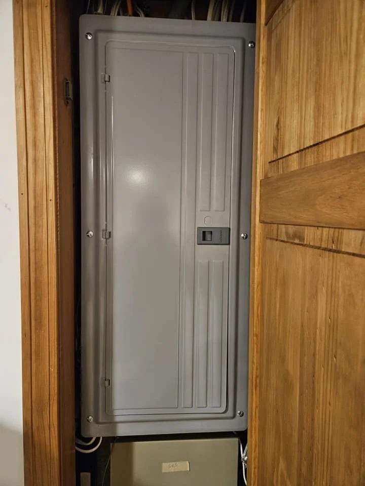 Gray electrical panel mounted between wooden wall panels.