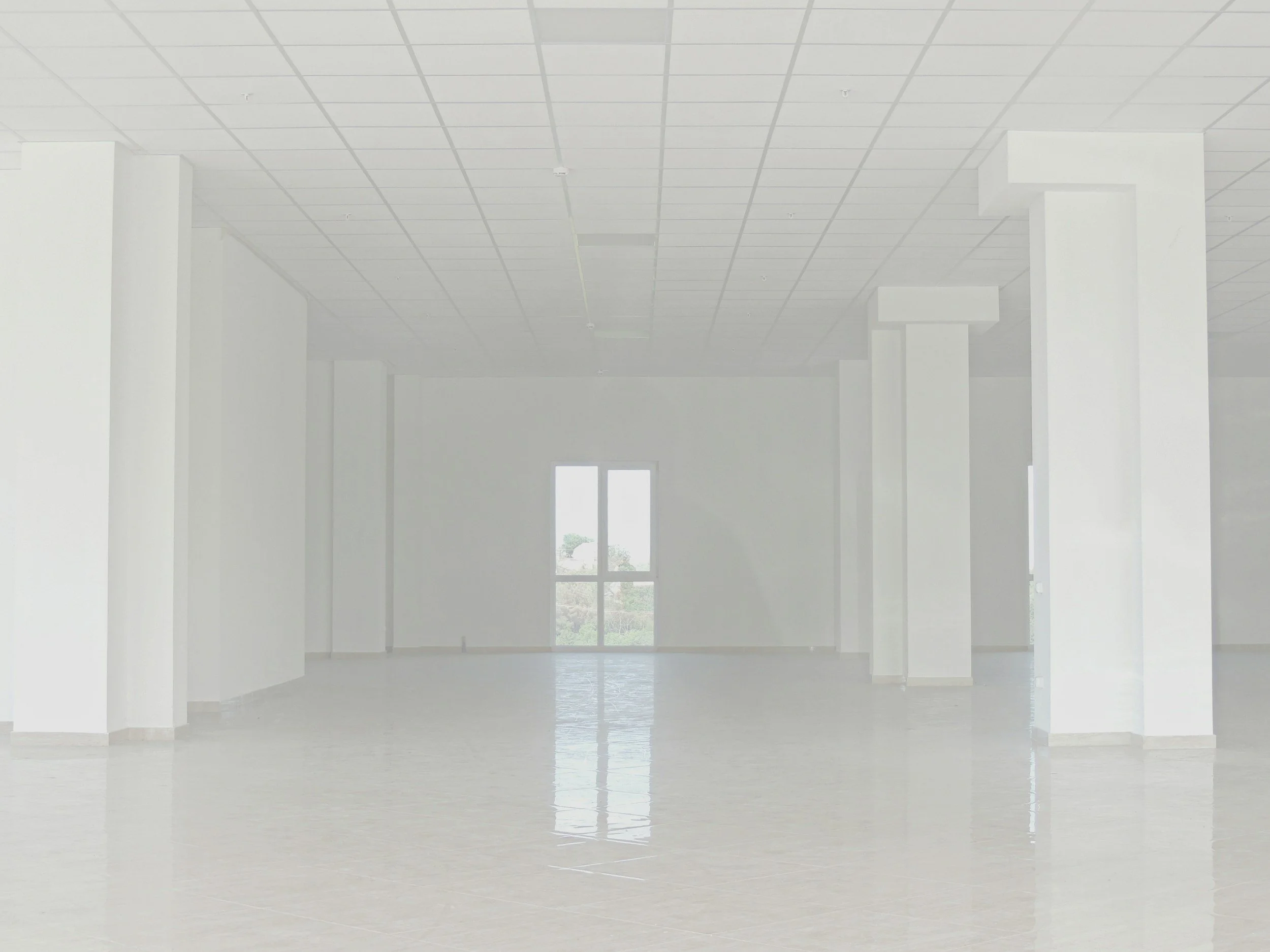 An empty room with large windows, white walls, and a shiny flooring.