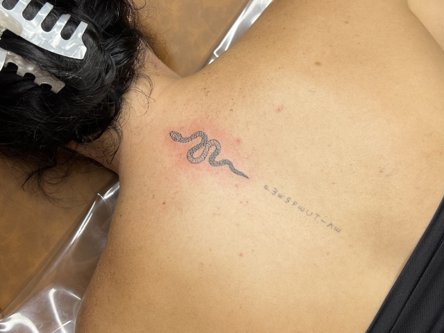 Ladies fine line tattoo of snake on upper spine by Banksia and Blade