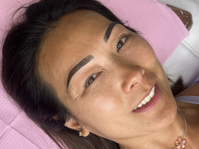 Close up lady smiling at camera after having her cosmetic brow tattoo completed by ashlea baldwin