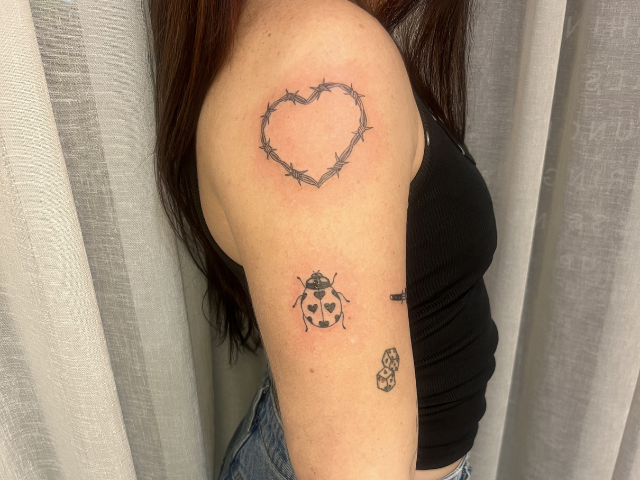 Barbed wire heart and lady bug tattoo on upper arm by banksia and blade