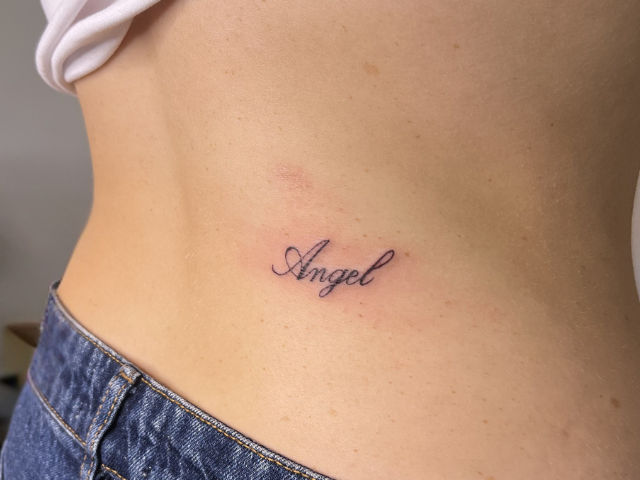 'angel' fine line tattoo on right lower back by banksia and blade