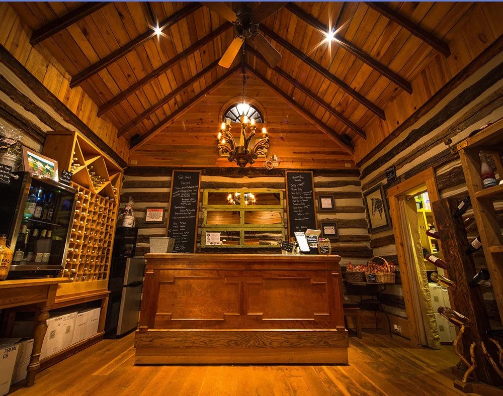 Rustic log-cabin tasting room at Tsali Notch Vineyard in Madisonville, TN, with a wooden bar, wine racks, and exposed beams