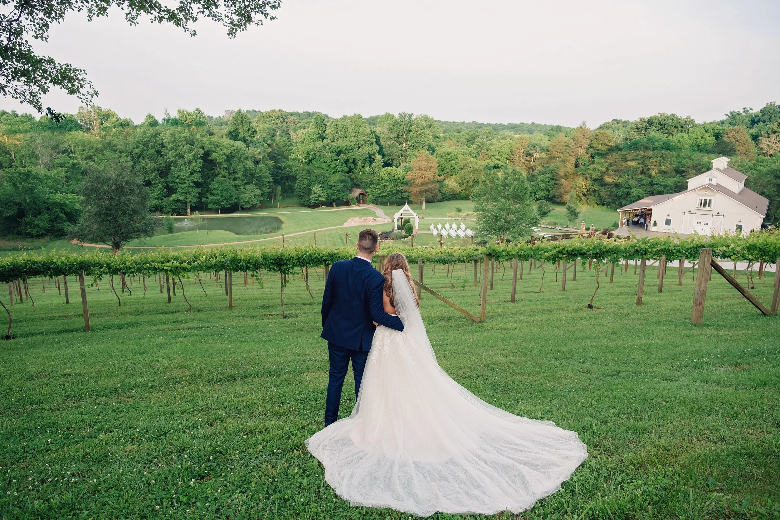 Bride and groom kissing beneath Ramble Creek’s natural vine arbor with white florals during a romantic March wedding ceremony in Tennessee.
