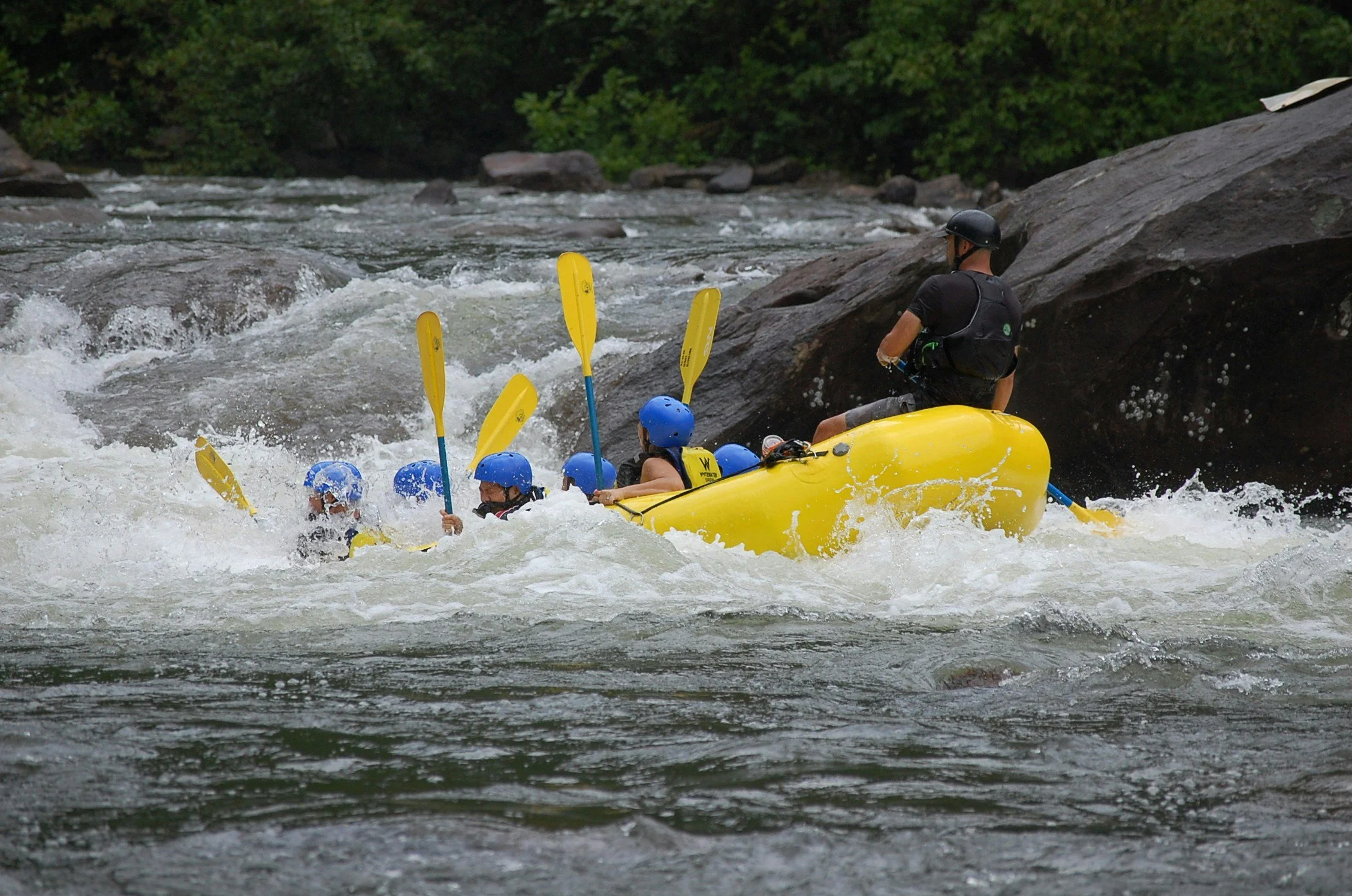 Paddles rise above the spray as rafters plunge through the Ocoee River’s whitewater, with forested banks and massive boulders framing the ride.