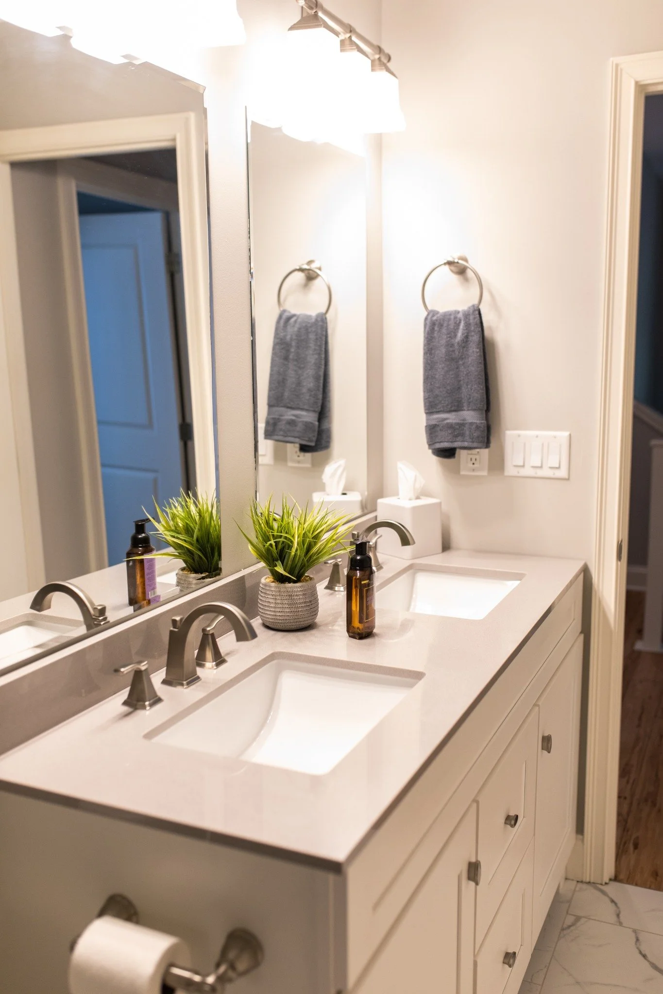 Bathroom at the Manor onsite accommodation at Ramble Creek, featuring a double vanity with white countertops, large mirror, gray towels, and modern neutral finishes.
