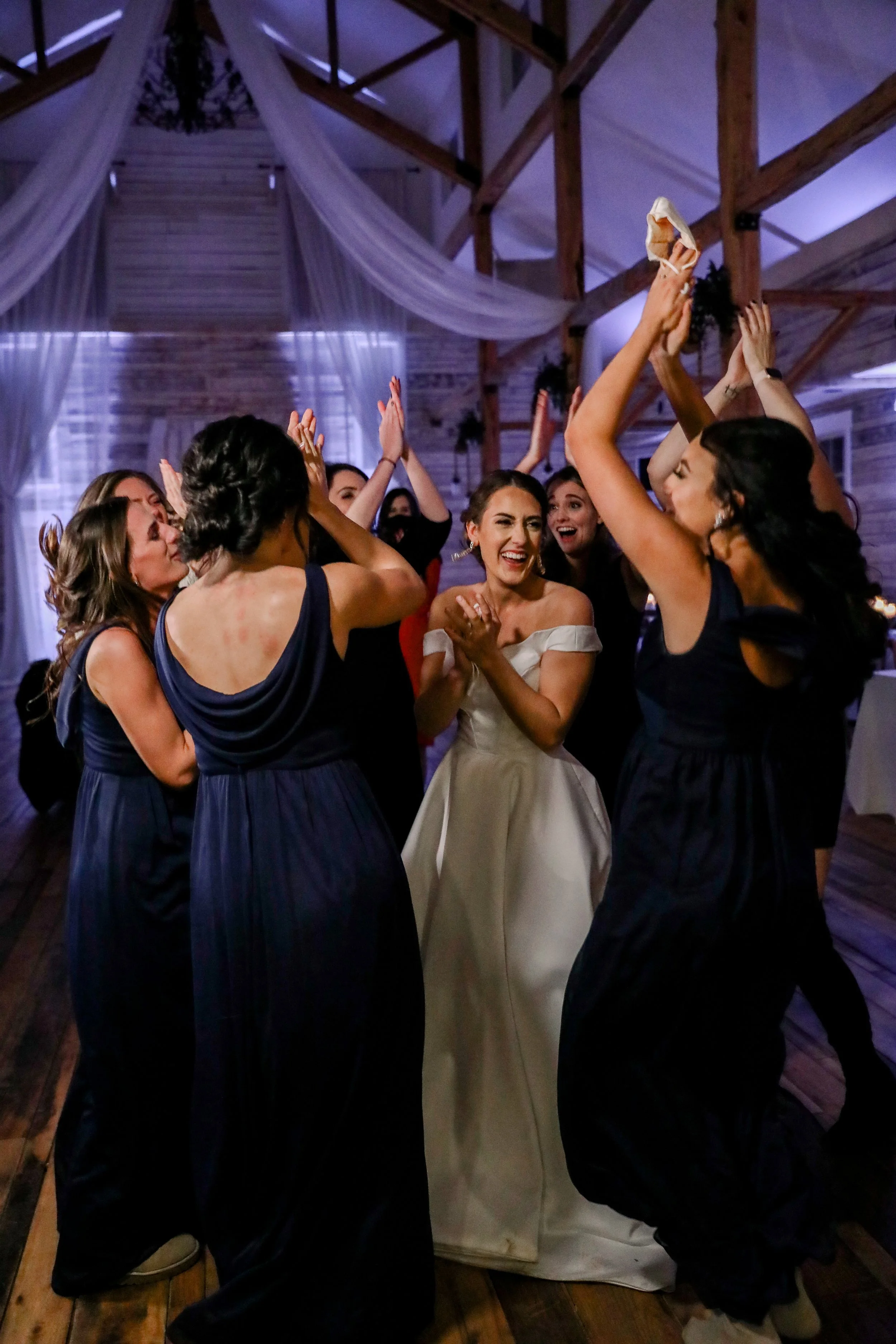 Bride and wedding guests dancing during an energetic wedding reception with DJ entertainment, uplighting, and draped ceilings at Ramble Creek wedding venue in Tennessee