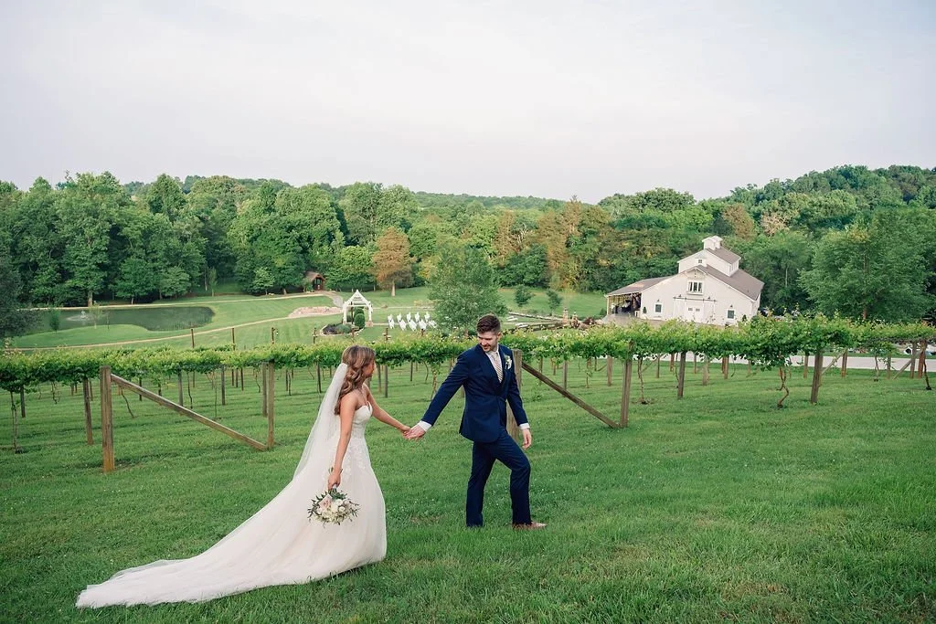 Bride and groom walking through vineyard overlooking Ramble Creek Tennessee wedding venue and ceremony site