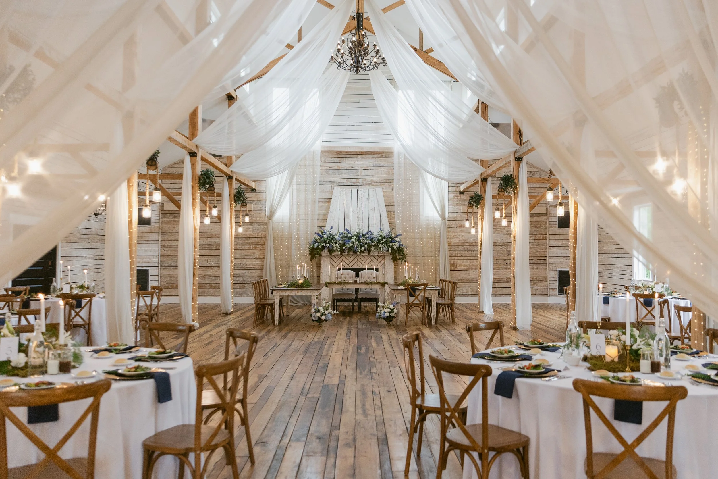 Elegant reception space at Ramble Creek with white draping, candlelit tables, and blue floral details for an all-inclusive East Tennessee wedding in Athens TN.