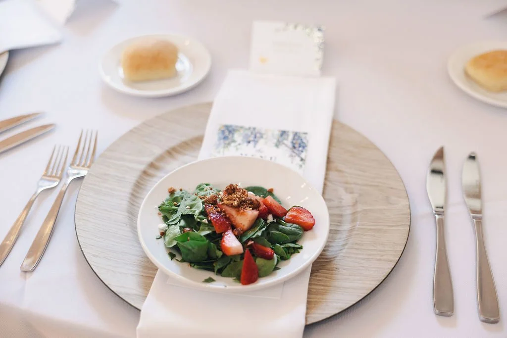 A plate of mixed greens with strawberries and toppings on a table set for a wedding reception dinner at Ramble Creek Tennessee wedding venue.