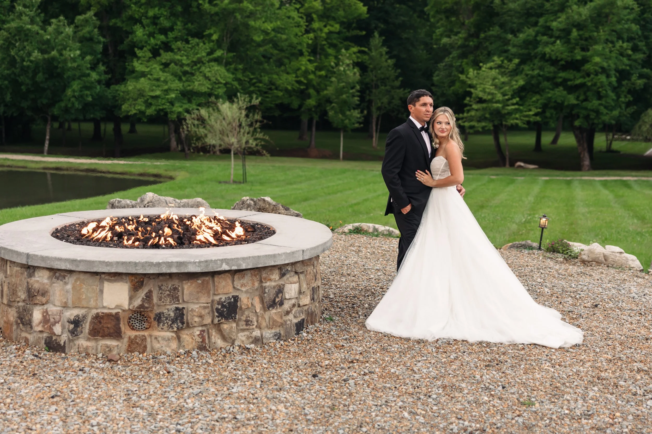 Bride and groom standing beside an outdoor fire pit at sunset during a romantic wedding evening at Ramble Creek wedding venue in Tennessee