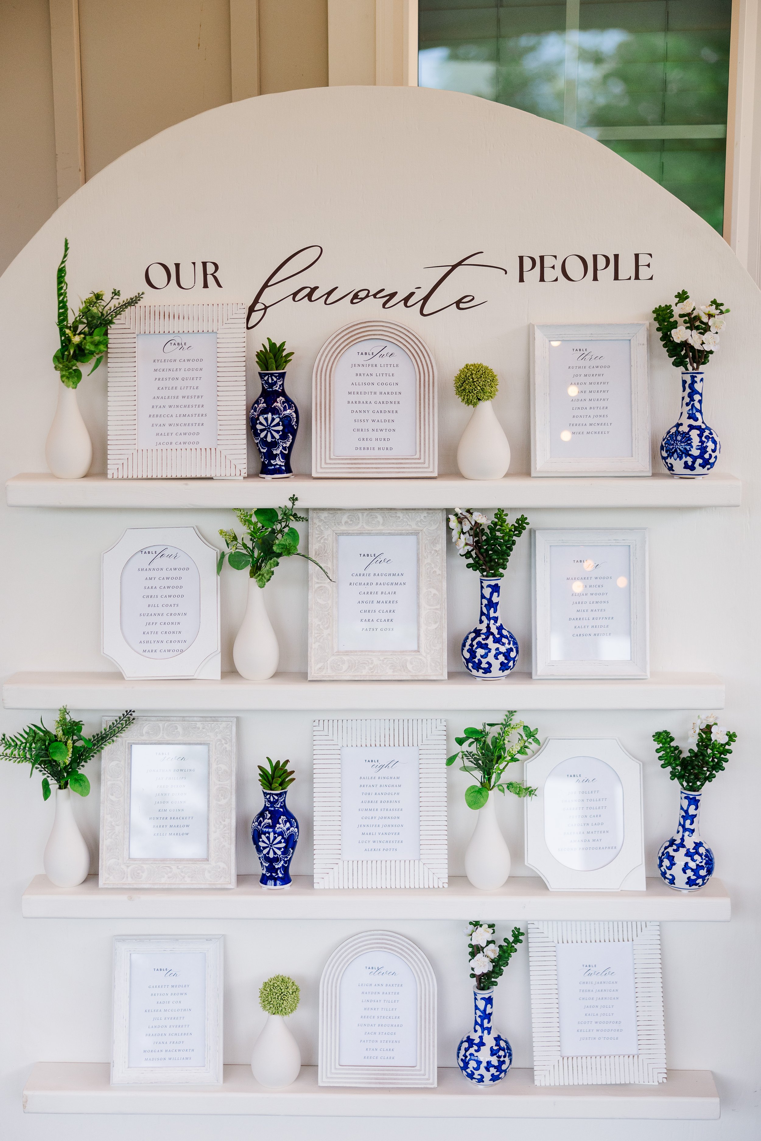 Wedding seating chart display at Ramble Creek Wedding Venue in Tennessee with framed table assignments, blue and white vases, greenery, and favorite people signage.