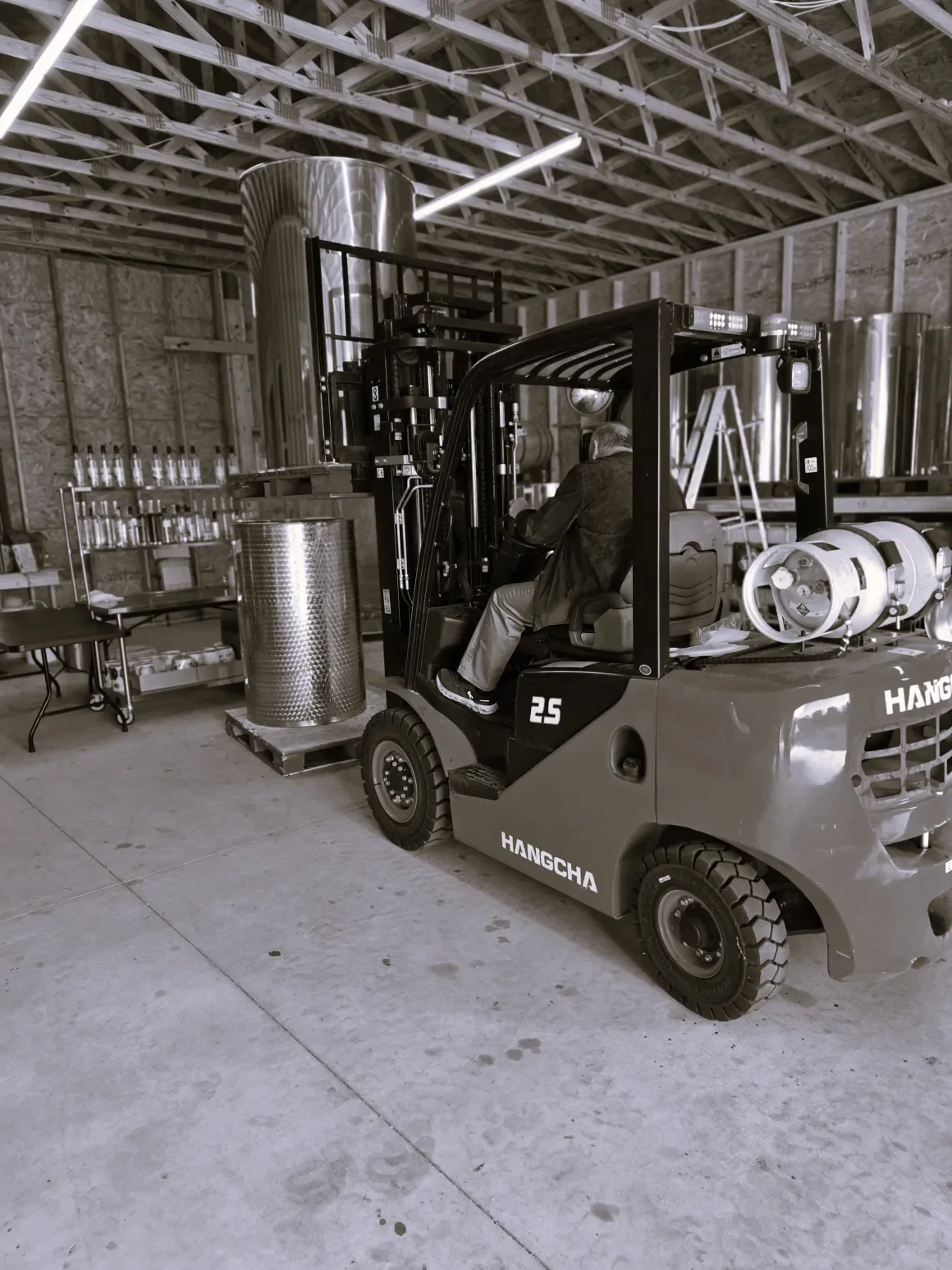 Forklift operator moving stainless steel equipment inside Morea Distillery in Riceville, near Athens, TN.