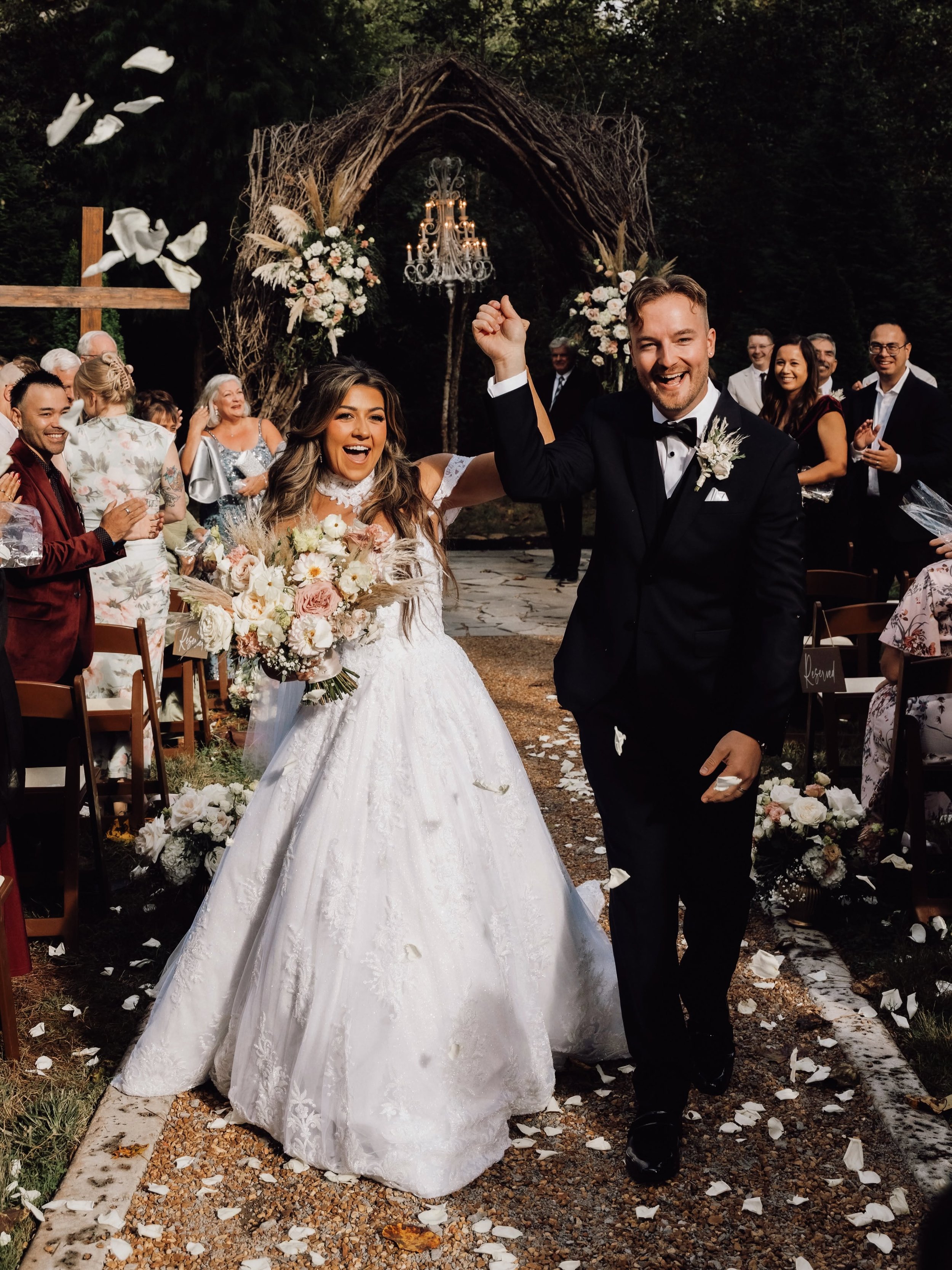 Kara Lewis and West Webb walk down the aisle hand in hand as guests toss petals after their Vine Arbor wedding ceremony at Ramble Creek in Athens, Tennessee