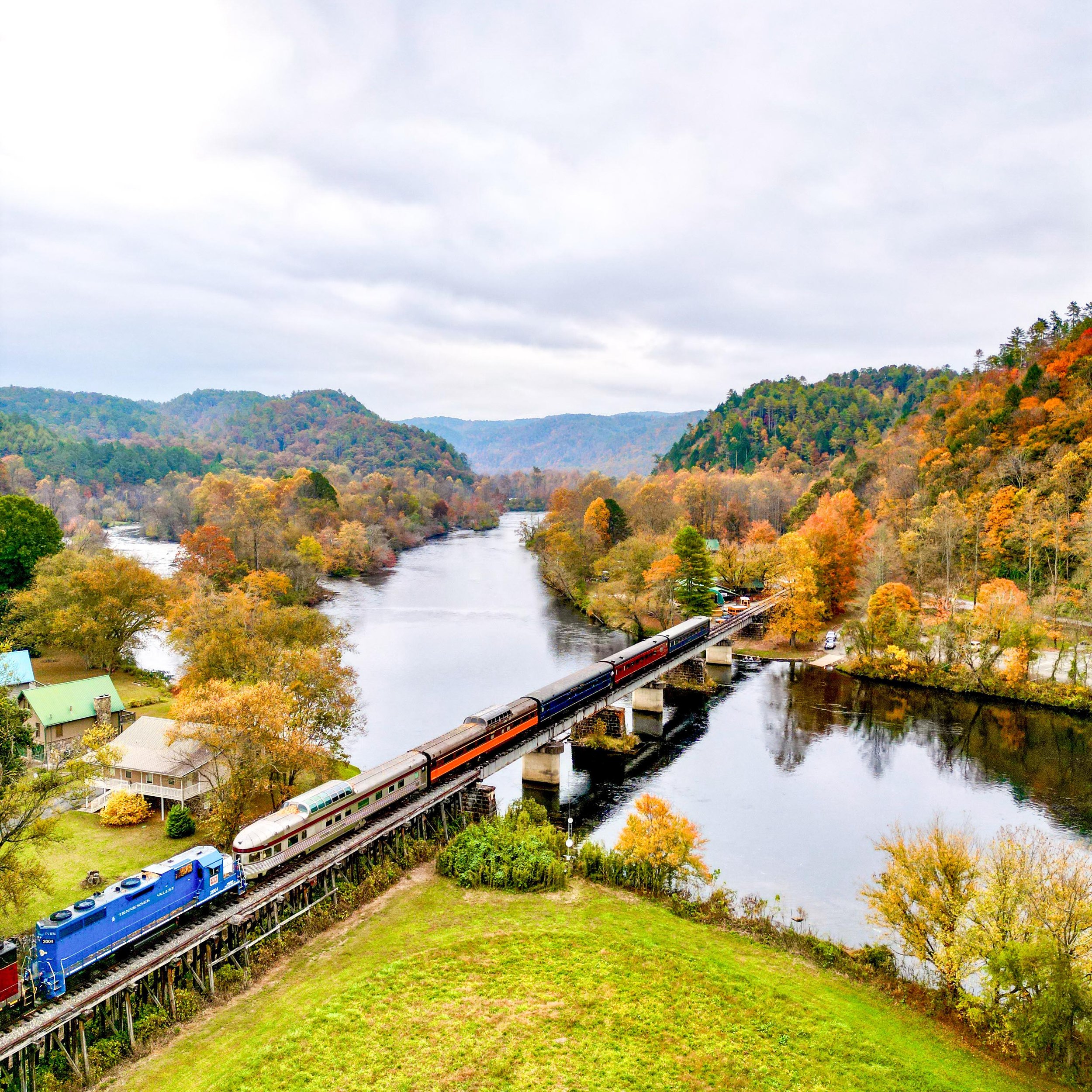 Follow the Hiwassee River into a gorge of wooded slopes and rocky bluffs, watching the water appear and disappear beyond the train windows.