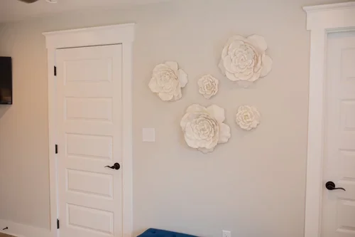 Bedroom detail inside the Villa at Ramble Creek, featuring white doors, neutral walls, and decorative white flower wall art.